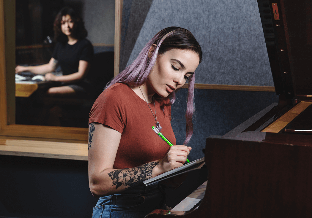 Woman writing music by piano